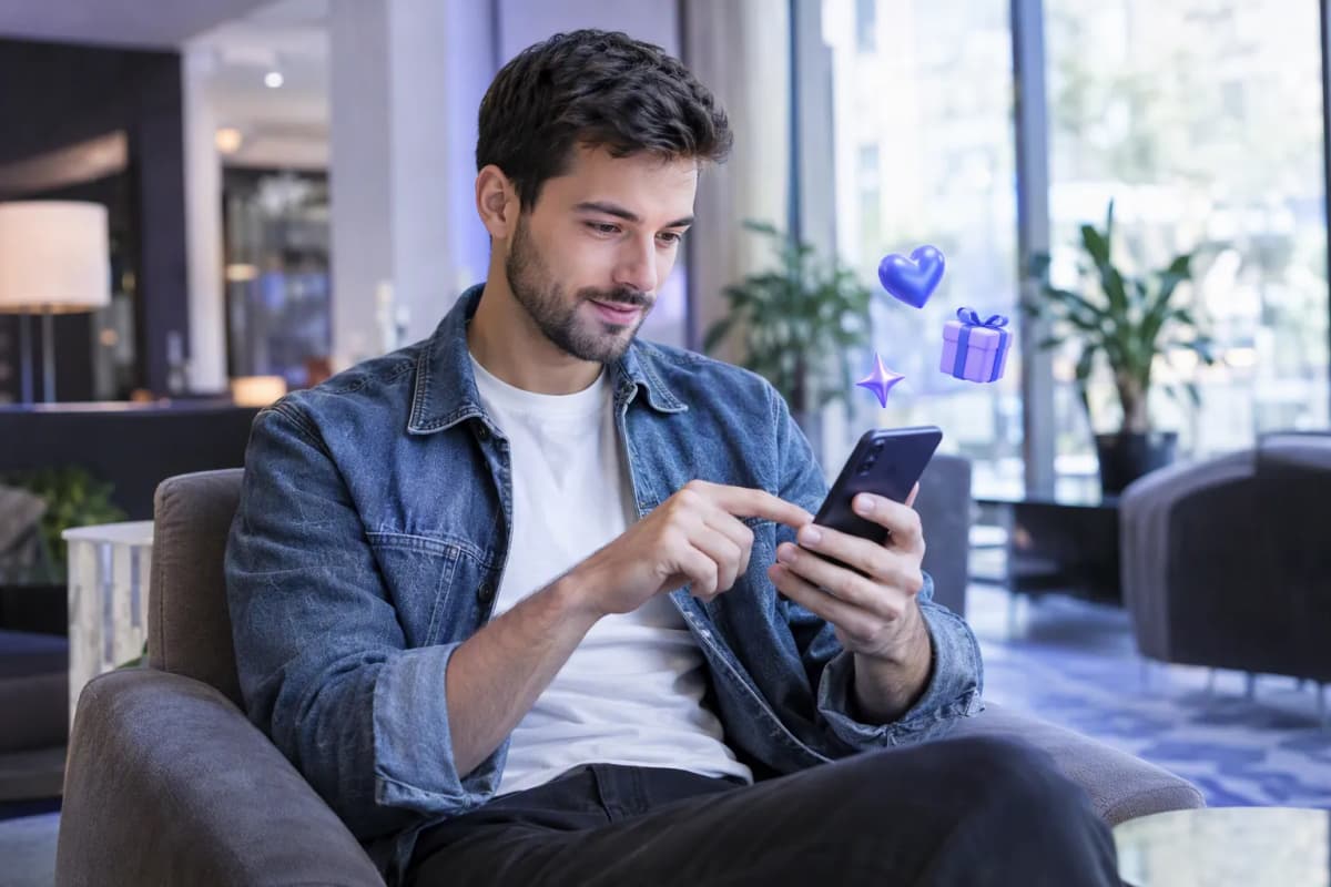 Otel lobisindeki koltukta telefonunda ücretsiz denemeyi keşfeden genç adam; çevresinde 3D simgeler