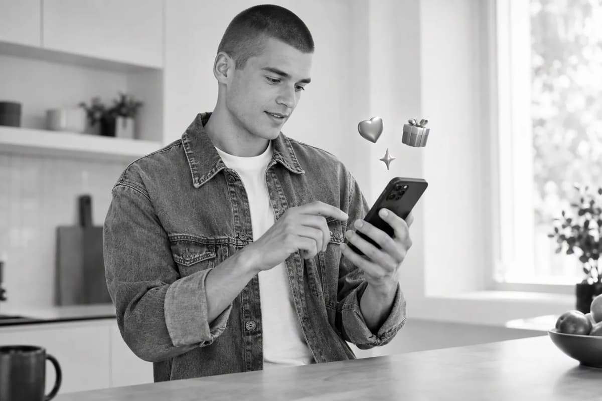 Sabah mutfak tezgâhında telefonunda ücretsiz denemeyi keşfeden genç adam; çevresinde 3D simgeler