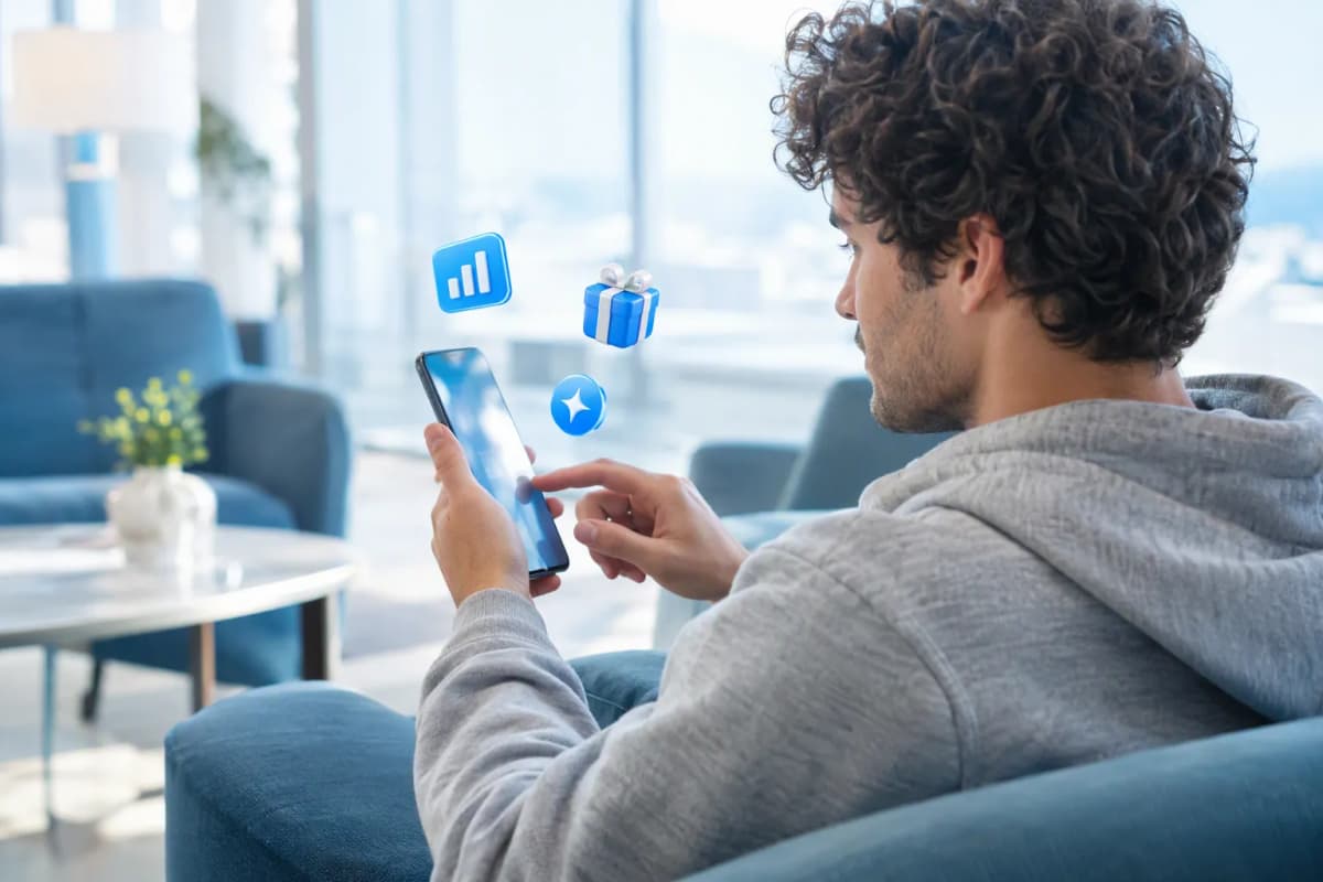 Otel lobisindeki koltukta telefonunda ücretsiz denemeyi keşfeden genç adam; çevresinde 3D simgeler